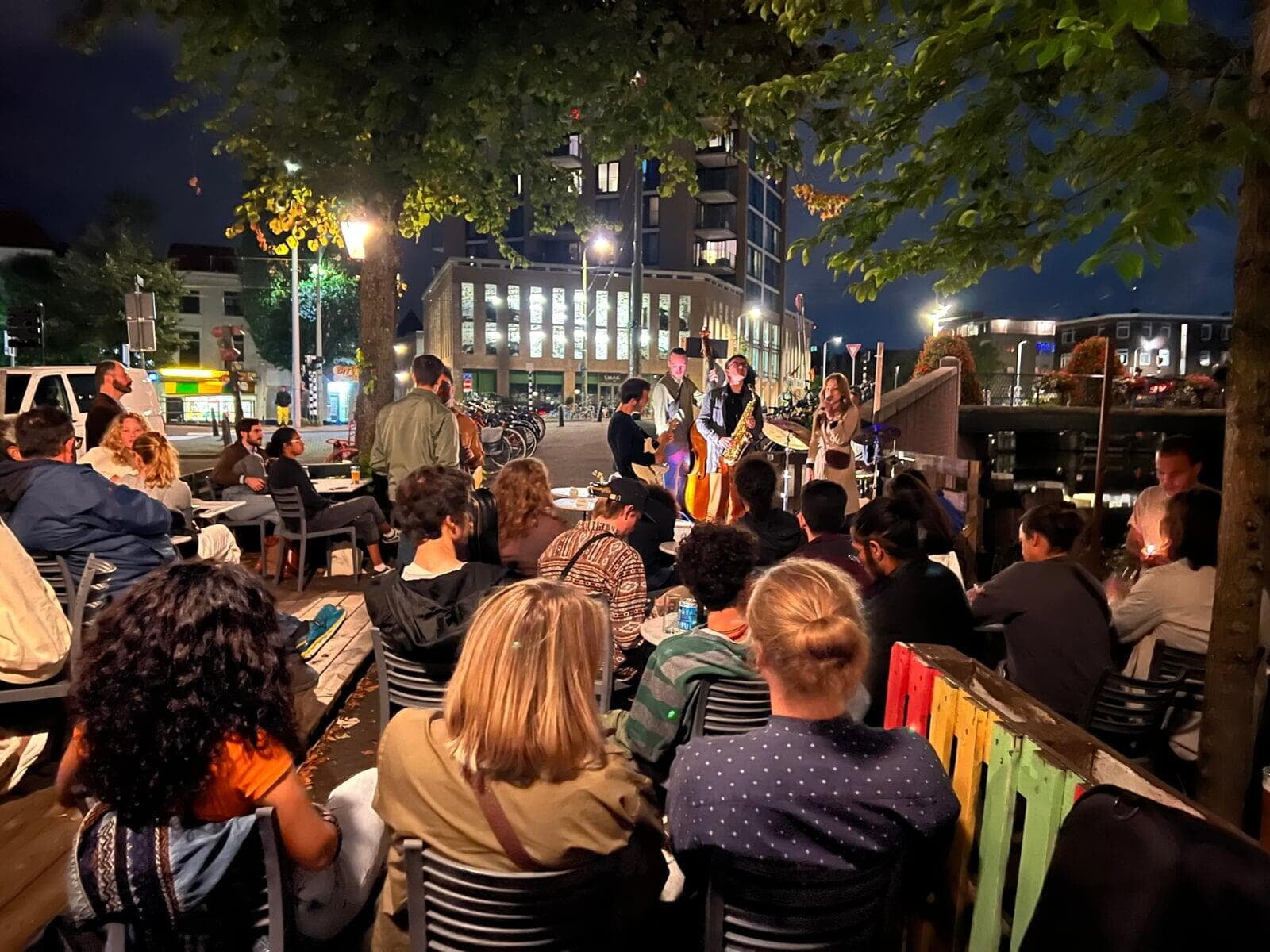Guests on the terrace on the Bierkade canal listening to a live band at night